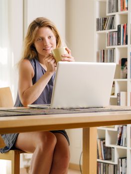 Photo of a beautiful young female shopping online and drinking coffee. 