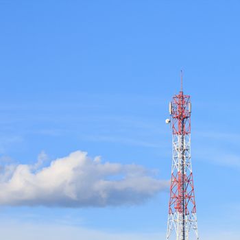 Red and white roof top cellular tower under blue sky