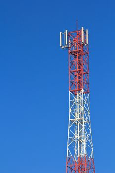 Red and white roof top cellular tower under blue sky