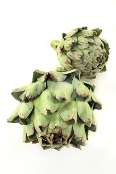 fresh, raw artichoke against a white background