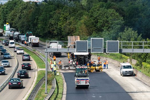 STUTTGART, GERMANY - AUGUST 10,2013: Workers laying asphalt on a public interstate (B27) during holiday season on August 10, 2013 in Stuttgart, Germany.