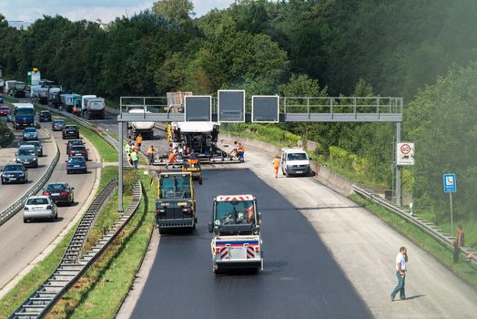 STUTTGART, GERMANY - AUGUST 10,2013: Workers laying asphalt on a public interstate (B27) during holiday season on August 10, 2013 in Stuttgart, Germany.