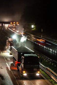 STUTTGART, GERMANY - AUGUST 16 ,2013: Workers removing asphalt on a public interstate (B27) using heavy machinery during holiday season on the evening of August 16, 2013 in Stuttgart, Germany.