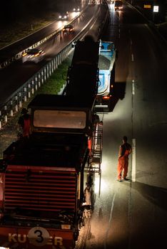 STUTTGART, GERMANY - AUGUST 16 ,2013: Workers removing asphalt on a public interstate (B27) using heavy machinery during holiday season on the evening of August 16, 2013 in Stuttgart, Germany.