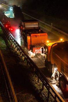 STUTTGART, GERMANY - AUGUST 16 ,2013: Workers removing asphalt on a public interstate (B27) using heavy machinery during holiday season on the evening of August 16, 2013 in Stuttgart, Germany.