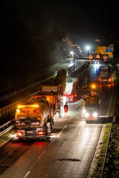STUTTGART, GERMANY - AUGUST 16 ,2013: Workers removing asphalt on a public interstate (B27) using heavy machinery during holiday season on the evening of August 16, 2013 in Stuttgart, Germany.