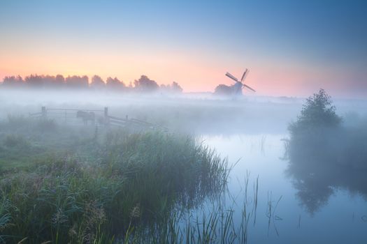 charming windmill by misty river at sunrise, Groningen, Netherlands