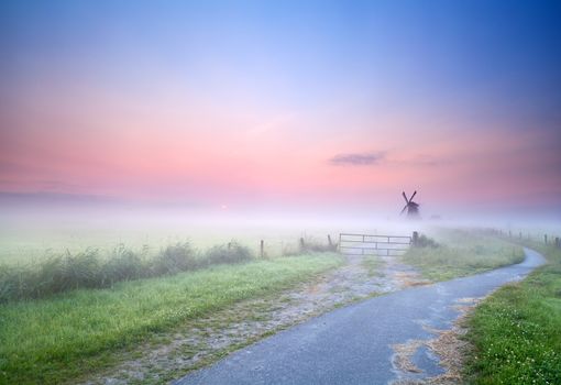 bicycle way to windmill in morning fog, Groningen, Netherlands