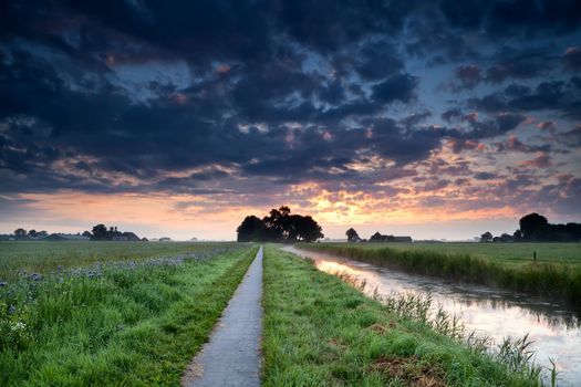 dramatic summer sunrise over farmland with canal and fields