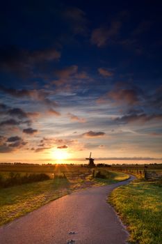 warm summer sunrise and way to Dutch windmill