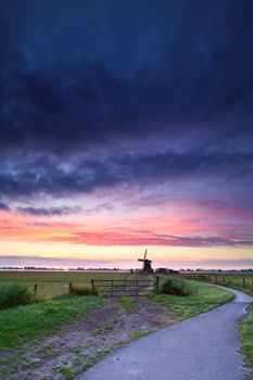 bicycle road to Dutch windmill in dramatic sunrise