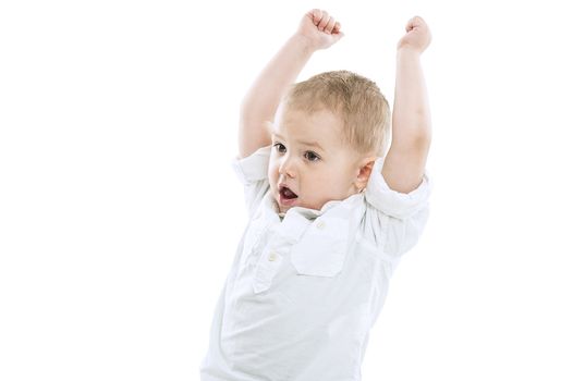 Excited playful handsome little boy standing with raised arms and his mouth open as though cheering isolated on a white background