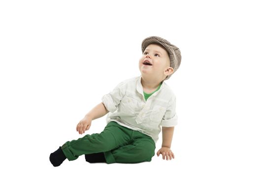 Image of a smartly dressed cute toddler boy sitting on the floor and laughing, isolated on white.