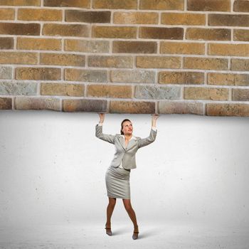 Image of businesswoman lifting brick wall above head