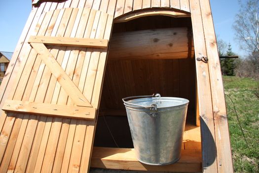 Vintage wooden well with a bucket in the summer in the countryside