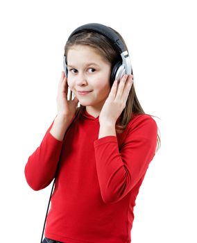 A smiling child girl listens to music through headphones on the white background