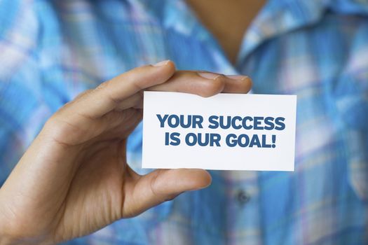 A person holding a white card with the words Your success is our goal