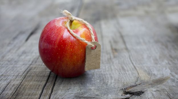 A Red Apple with a Price Label on wood background