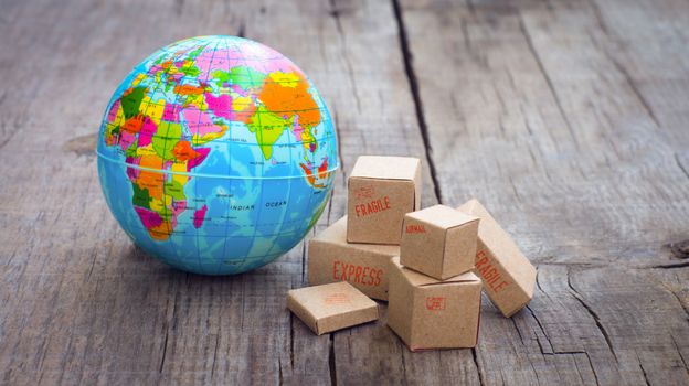 Miniature globe and boxes on wooden background