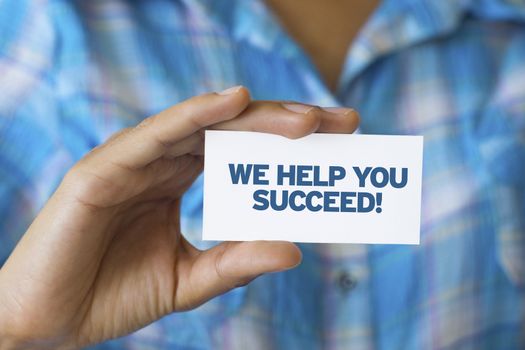A person holding a white card with the words We help you Succeed