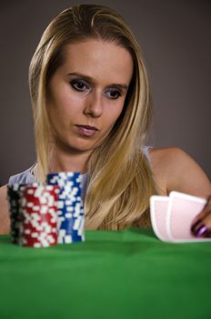 woman playing poker lifting her cards thinking about the game