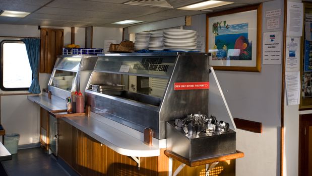 Galley or catering area a food warmers for a buffet on board a boat with stacked plates and cutlery ready for the next meal