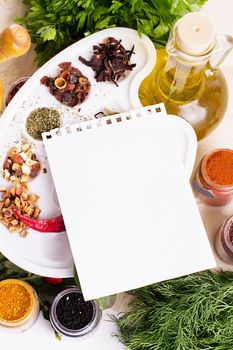 Blank notebook sheet with spices and herbs on the wooden board