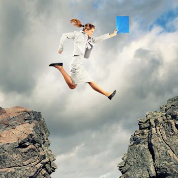 Image of young businesswoman jumping over gap