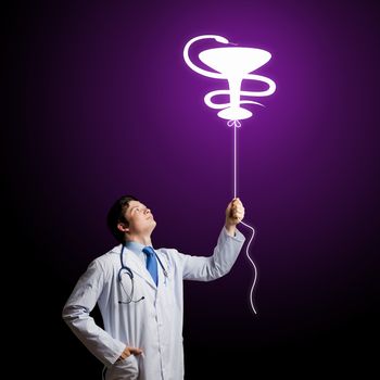 Young male doctor holding balloon with medicine sign