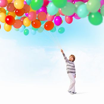 Little cute boy playing with bunch of colorful balloons