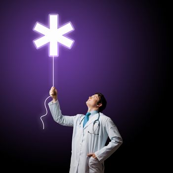 Young male doctor holding balloon with medical sign