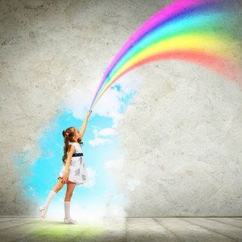 Image of little pretty girl drawing rainbow with finger