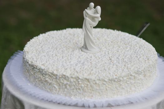 White wedding cake with white figures of bride and husband