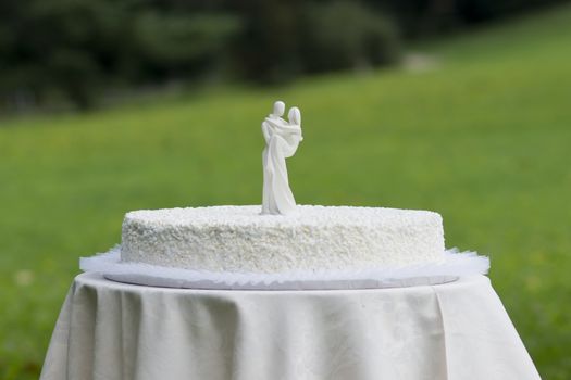 White wedding cake with white figures of bride and husband