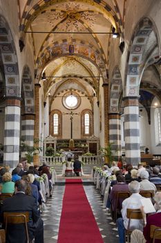 Couple seen from the bottom of the aisle of a romanic church, while they're getting married 