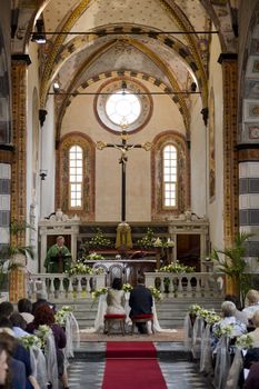 Couple seen from the bottom of the aisle of a romanic church, while they're getting married 