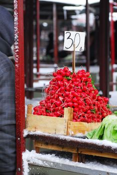 heap of red radish in wooden container in outdoor market at winter