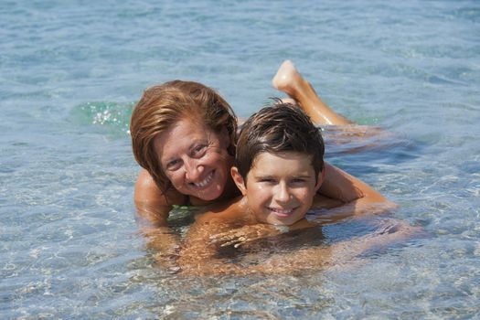 Father and son liying in the sea in Sardinia