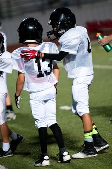 Young football boy putting his arm around his teamate.