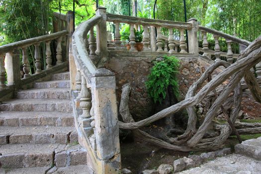 Ornamental stone bridge with steps curving away towards a lush green forest or woodland in a park