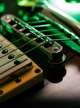 Macro abstract photo of the pickup, bridge and strings of an electric guitar. Shallow depth of field with focus on the first string.