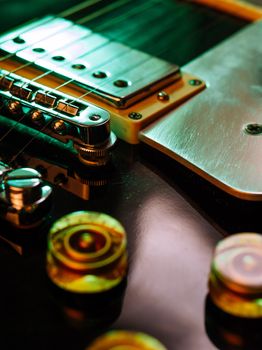 Macro abstract photo of the pickups, bridge and knobs of an electric guitar. Shallow depth of field with focus across the middle.
