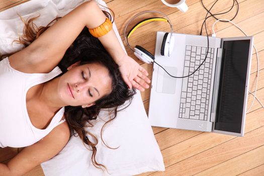 A girl laying on the Floor after surfing on the Internet with a Laptop.