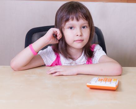 Asian girl with a calculator sitting at office desk