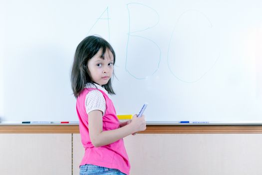 Child at whiteboard writing ABC