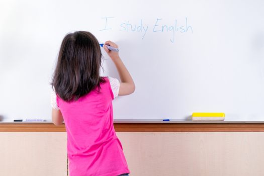 Child at whiteboard writing I study English