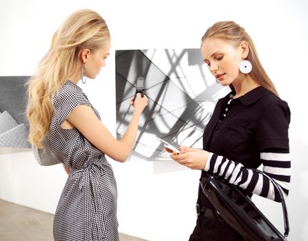 girl-friend with mobile phones at an exhibition 
