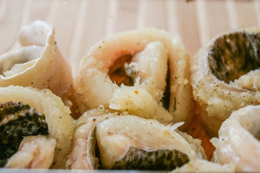 Pieces of traditional Polish pickled herring in a glass container.