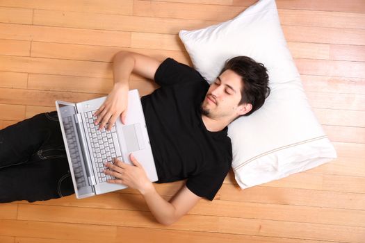 A young hispanic man surfing with a Laptop on the floor.