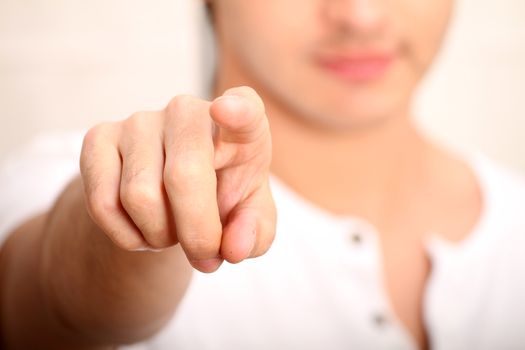 A young man pointing at you. Focus on Finger.